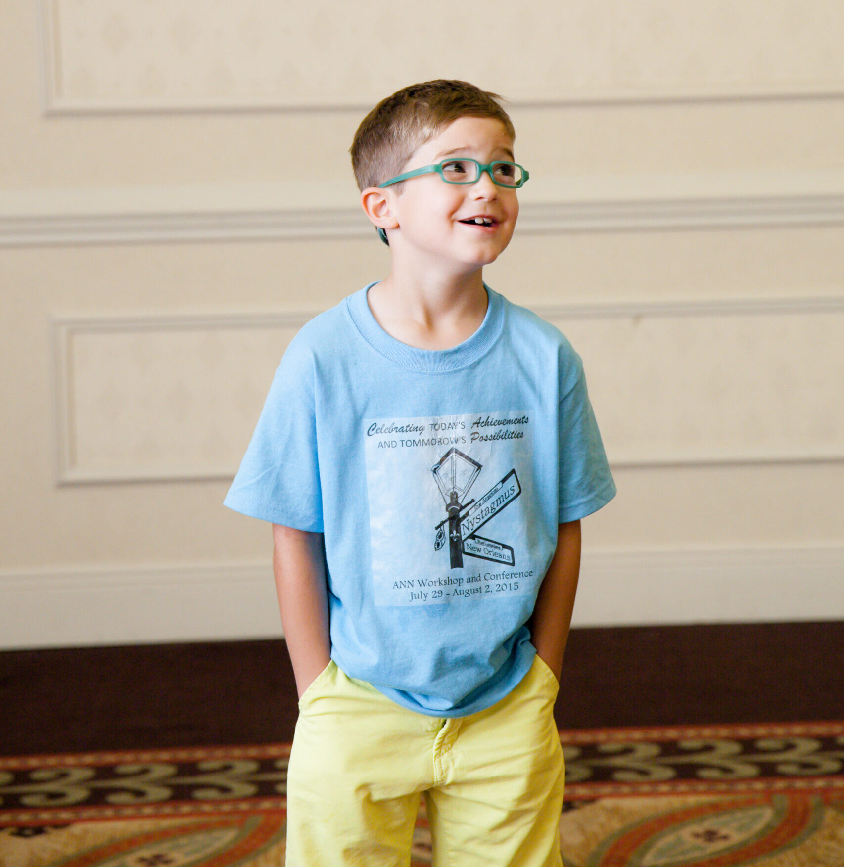 Boy with glasses smiling and looking to the side.